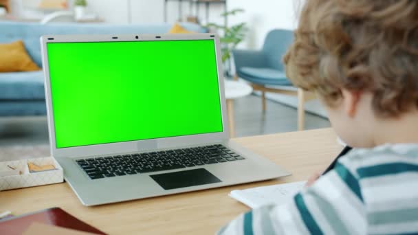 Boy writing and working with laptop doing homework in apartment during covid-19 lockdown — Stock Video