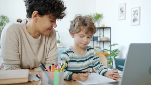 Matka učí malého chlapce mluvit při pohledu na notebook psaní obrazovky v notebooku doma — Stock video
