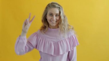 Sarı arka planda dans eden genç ve çekici sarışın portresi