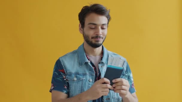 Overjoyed Middle Eastern man holding passport with plane ticket kissing document expressing happiness — Stock Video