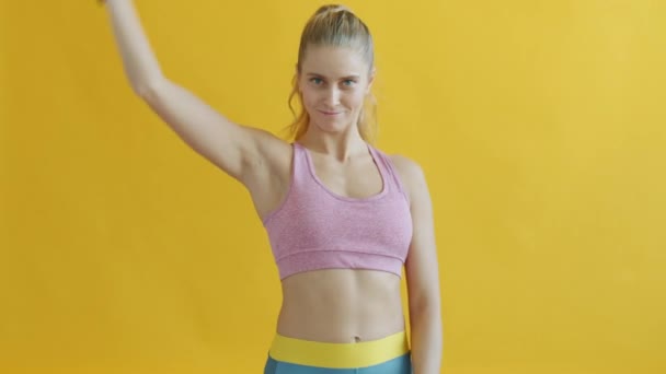 Portret pięknej młodej kobiety w sportowym staniku poruszającej wstążkę gimnastyczną artystyczną — Wideo stockowe