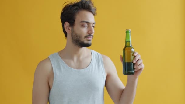 Jonge Arabische sportman die naar bierflesjes kijkt en dan zegt dat hij geen alcohol mag vermijden — Stockvideo