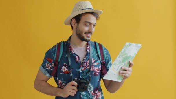 Retrato en cámara lenta del tipo árabe con mochila y cámara fotográfica mirando el mapa y sonriendo — Vídeos de Stock