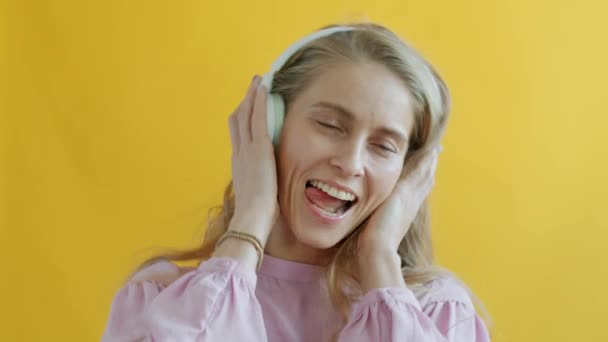 Portrait au ralenti de jeune femme écoutant de la musique avec des écouteurs dansant en regardant la caméra — Video