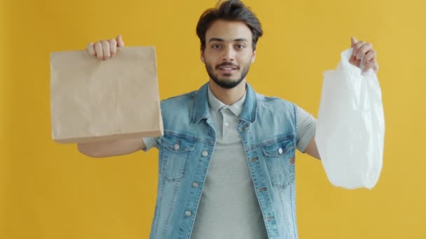 スローモーションポートレートの中東男選択紙袋上のプラスチックと笑顔 — ストック動画