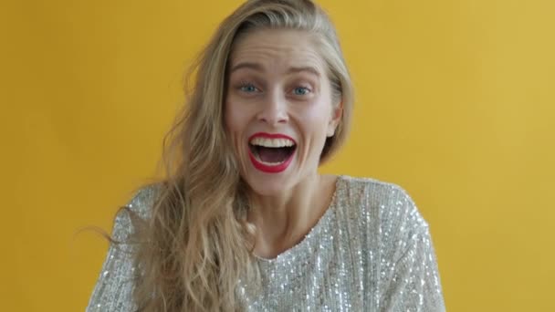 Slow motion av glad dam skrattar sedan blåsa silver gnistrar på gul bakgrund — Stockvideo