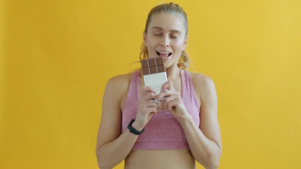 Retrato de alegre senhora de esportes cheirando cololato, em seguida, comer e sorrir no fundo amarelo — Vídeo de Stock