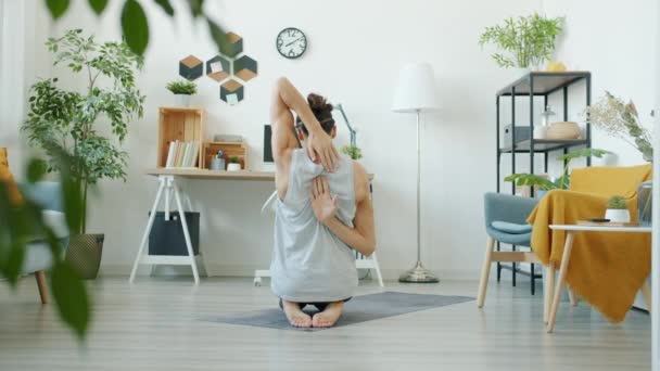 Movimiento lento del chico haciendo ejercicio de yoga estirando los músculos de los brazos en el interior de casa — Vídeo de stock