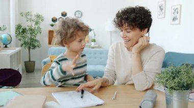 Çocuk ev ödevi yapıyor. Annesiyle sarılıyor, evde beşlik çakıyor.