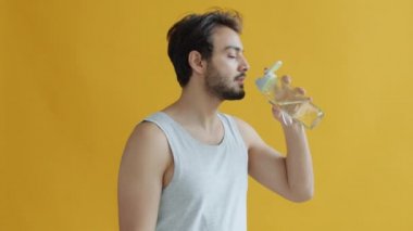 Şişeden su içen Hintli genç sporcunun yavaş çekim portresi. Sonra kameraya bakıp gülümsüyor.
