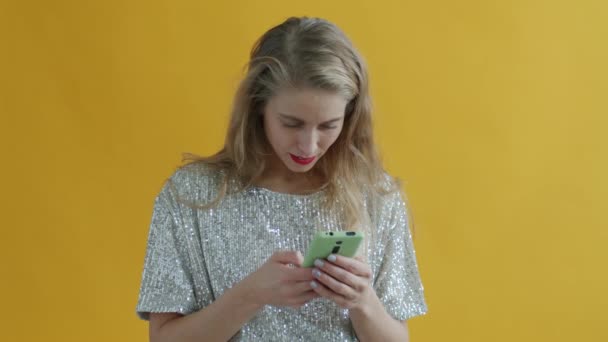 Медленное движение молодой женщины с помощью смартфона получает хорошие новости, а затем конфетти падает вокруг — стоковое видео
