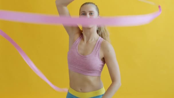 Retrato de una joven gimnasta entrenando con cinta sonriente mirando a la cámara — Vídeo de stock