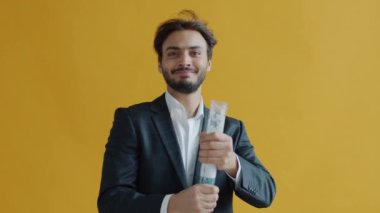 Orta Doğulu bir adamın konfeti fırlatıp, sarı arka planda dans edişinin yavaş çekim portresi.
