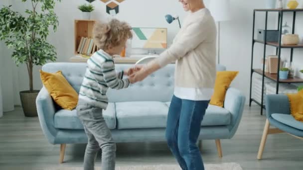 Slow motion van vrolijke kind dansen met jonge actieve moeder plezier hebben samen thuis — Stockvideo