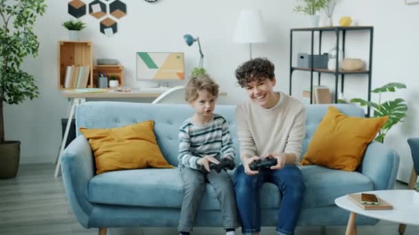 La cámara lenta de la mujer joven y el hijo jugando videojuegos juntos en el apartamento — Vídeo de stock