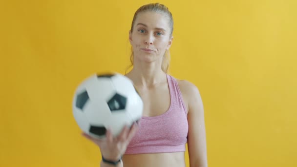 Πορτρέτο της νεαρής αθλήτριας κρατώντας το ποδόσφαιρο δείχνει κόκκινη κάρτα και κοιτάζοντας την κάμερα — Αρχείο Βίντεο