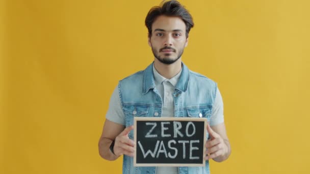 Retrato em câmera lenta de um cara sério do Oriente Médio segurando o banner Zero Waste — Vídeo de Stock