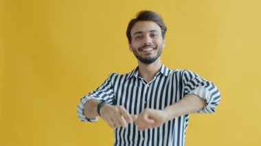 Çekici Orta Doğulu adamın portresi sarı arka planda dans ediyor.