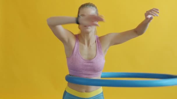 Slow motion av smal kvinna tränar med hula båge träna ensam på gul bakgrund — Stockvideo