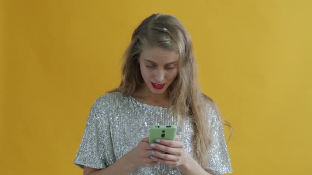 Молодая женщина получает хорошее сообщение на смартфоне, а затем смотреть конфетти падает — стоковое видео
