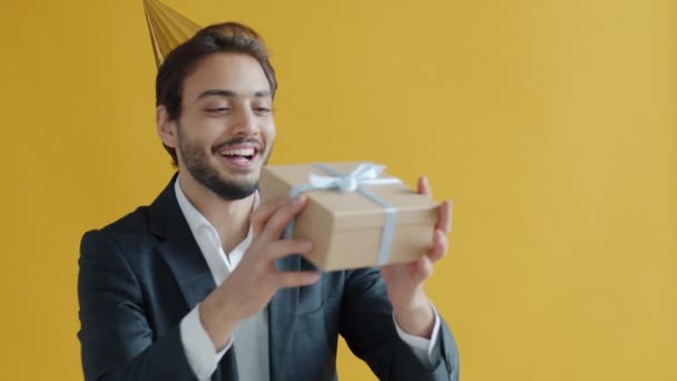 Retrato en cámara lenta de hombre de raza mixta atrapando caja de regalo y sonriendo disfrutando presente — Vídeo de stock