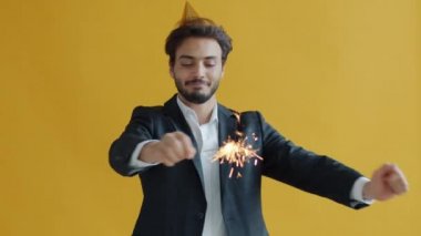 Mutlu Arap adam parti şapkası takıyor Bengal ışığıyla dans ediyor tatilin tadını çıkarıyor