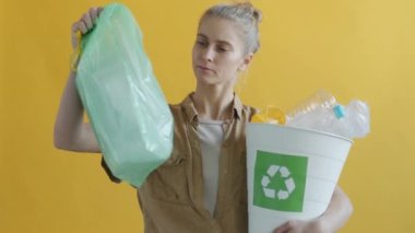 Yeniden kullanılabilir plastik torbalar taşıyan genç bir kadının yavaş çekim portresi.