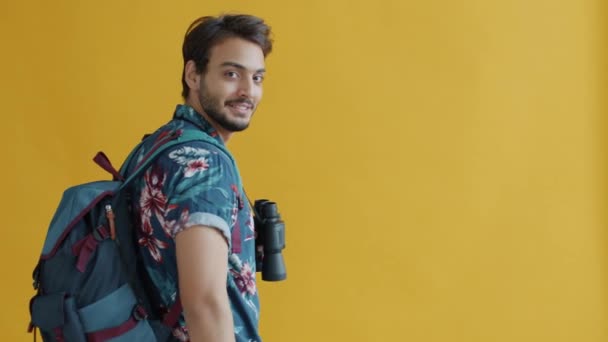 Slow motion portret van gemengde ras reiziger met rugzak en verrekijker draaien naar camera en glimlachen — Stockvideo