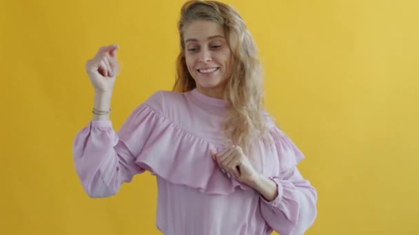 Retrato de menina atraente dançando curtindo festa no fundo de cor amarela. — Vídeo de Stock