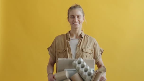 Portret van een jonge vrouw met een doos kartonnen afval met recyclingsymbool — Stockvideo