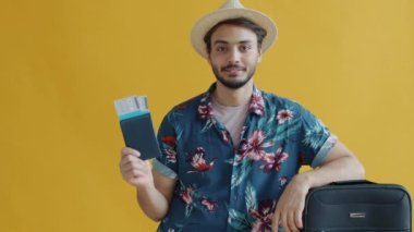 Seyahat pasaportu ve bileti gösteren bavullu Arap adamın portresi.
