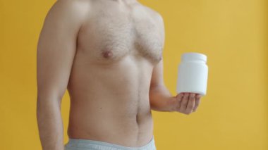 Erkek eli kavanozu spor besleyicisiyle işaret ediyor ve baş parmak hareketi yapıyor.