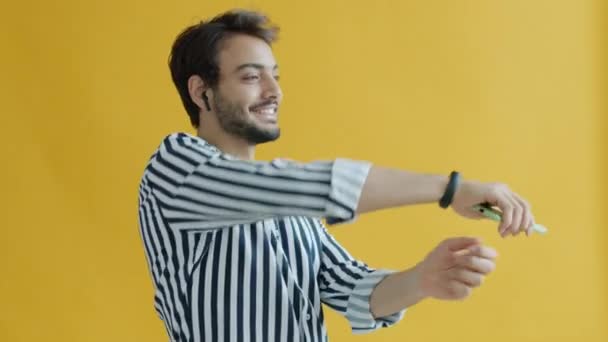 Portrait of Indian guy using earpods and smartphone dancing having fun — Stock Video