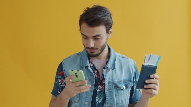 비행기 표로 여권을 들고 스마트폰 화면에 손을 대는 행복 한 아랍 남자 — 비디오