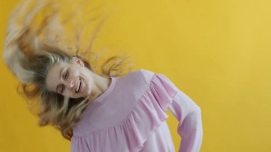 Güzel bir kadının dans etmesi ve sarı arka planda sarı saçlarla oynaması.
