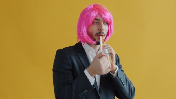 Homem do Oriente Médio vestindo peruca rosa dançando e bebendo coquetel de vidro — Vídeo de Stock