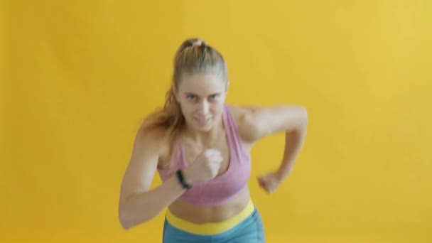 Portret aktywnej dziewczyny w sportowym joggingu uśmiechniętej ćwiczącej na żółtym tle — Wideo stockowe