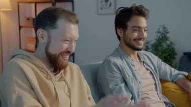 Televizyon seyreden rahat öğrenciler film izleyip bira içiyorlar. Aydınlanmış bir dairede eğleniyorlar.