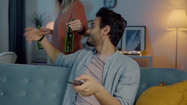 无忧无虑的女人带着一瓶啤酒去男朋友那里看电视 晚上在家里喝酒 关系和青年生活方式概念 — 图库视频影像