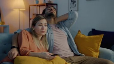 Uykulu genç bir çift TV seyrediyor. Geceleri evde konuşuyor ve sarılıyorlar.