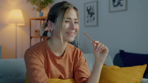 Portrait of pretty biracial woman watching funny comedy on TV and eating snacks enjoying evening at home — Stock Video