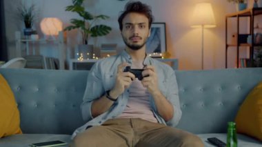 Karanlık evde elinde joystick ile video oyunu oynayan genç duygusal bir adamın portresi.