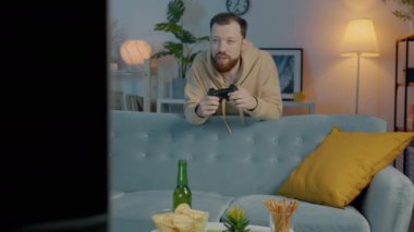 Heyecanlı bir öğrencinin portresi TV ekranına bakıp gece evde zaferi kutlayan joystick fırlatıyor.