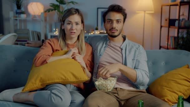 Portré boldog férj és feleség néz ijesztő sorozat ölelés eszik popcorn sötét szobában otthon — Stock videók