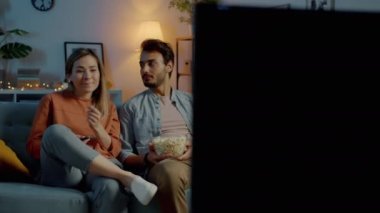 Genç çift uzaktan kumanda için kavga ediyor. Geceleri evde televizyon izliyorlar.