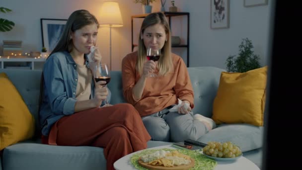 Amis féminins regardant la télévision boire du vin rouge et pleurer à l'intérieur à la maison la nuit — Video