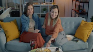 Güzel genç kadınlar kırmızı şarap içip konuşuyorlar ve akşamları karanlık bir evde televizyon izliyorlar.