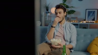 Orta Doğulu yorgun insan patlamış mısır yiyor televizyon seyrediyor ve geceleri evde dinleniyor.