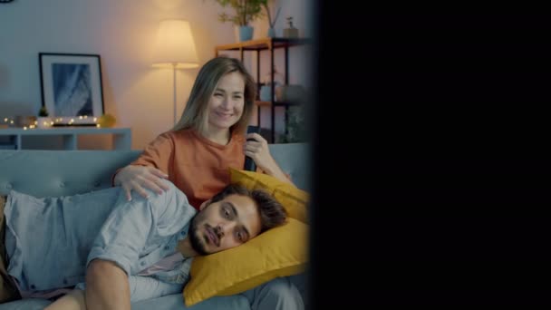 Man en vrouw rotzooien rond tv kijken en plezier hebben samen in donker huis — Stockvideo