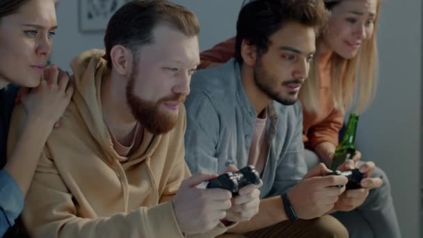 Amigos alegres grupo multicultural jugando videojuego relajante en el apartamento por la noche — Vídeos de Stock
